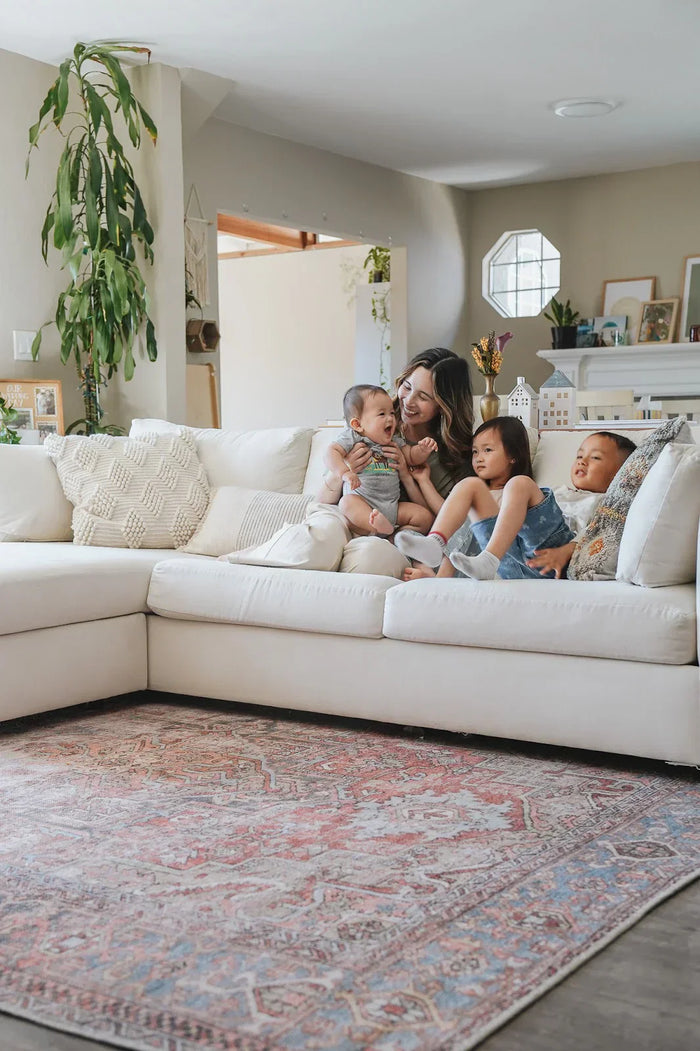 Mom playing with three young kids on white sofa